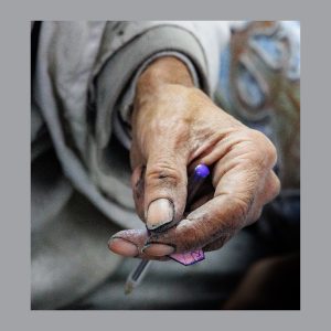 a hand covered in blue ink holds a ballpoint pen